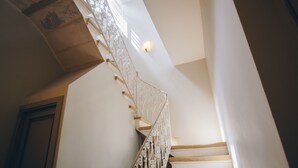 Un escalier orné de rampes en métal ouvragé et d’un luminaire placé au-dessus.