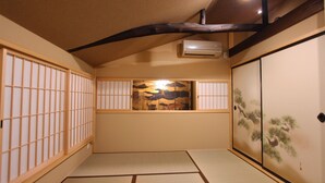 A traditional Japanese room with tatami flooring, sliding doors, and a decorative alcove with a painting. - Kyomachiya Ebisu (Kyoto)