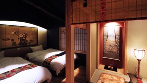 A traditional Japanese-style room with tatami flooring, two beds with white bedding, a shoji screen, and a hanging lantern. - Kyomachiya Ebisu (Kyoto)
