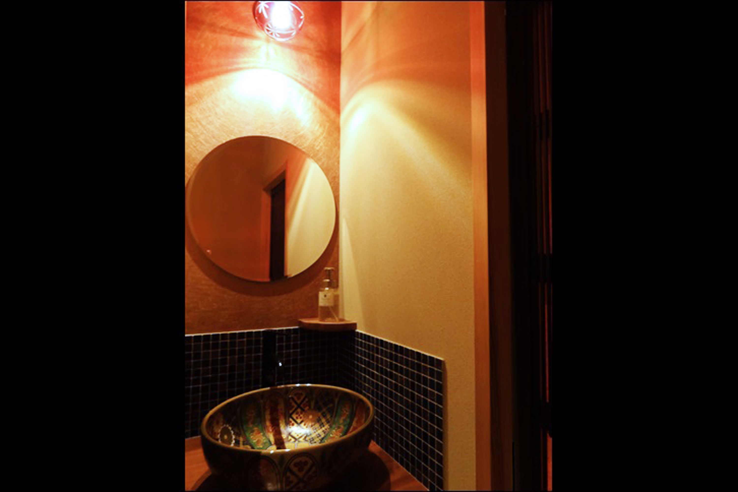 A bathroom with a round mirror, a sink, and a wall-mounted light fixture.