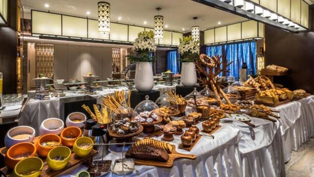 A buffet spread with various food items and a modern interior with hanging lights and decorative plants. - Braira Al Wezarat (Riyadh)