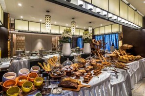 Ein reichhaltiges Buffet mit verschiedenen Speisen, ein modernes Interieur mit Hängeleuchten und Zimmerpflanzen.