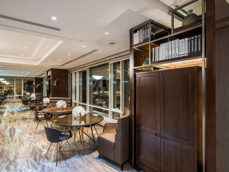 A modern interior with a marble floor, round tables, and dark wood furniture.