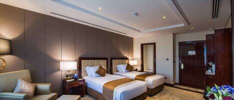 A hotel room with two beds, a sofa, a small table, a nightstand, a mirror, and a door.
