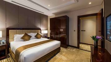 Un dormitorio de hotel con una cama grande, un armario, un escritorio con lámpara y una televisión.
