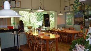 Un comedor con mesas y sillas de madera, un menú en una pizarra y certificados enmarcados en la pared.