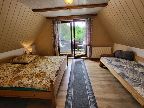 Une chambre avec deux lits, une fenêtre avec des rideaux, un plafond en bois et une vue sur l’extérieur.