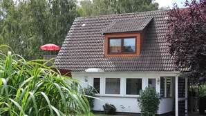 Ein Haus mit einem geneigten Dach, einem kleinen Fenster und einer Veranda.