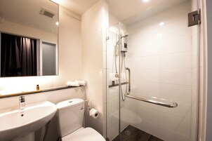 Un baño moderno con ducha de vidrio, lavamanos blanco y retrete.