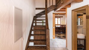 Un escalier en bois mène à une salle à manger d’où l’on peut apercevoir la cuisine et la salle de bain.