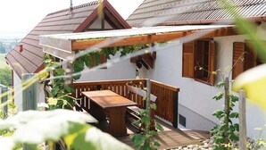 Une maison avec une terrasse en bois, une petite table et une fenêtre dotée de volets en bois.
