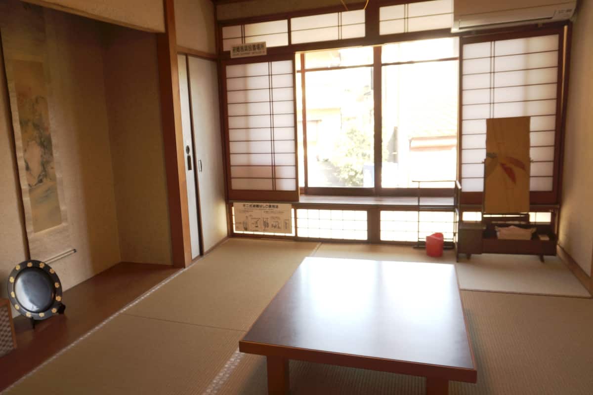 Ein traditioneller japanischer Raum mit Tatami-Bodenbelag, Shoji-Schirmen und einem niedrigen Holztisch.