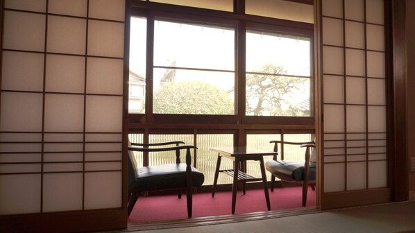 A traditional Japanese room with tatami flooring, a sliding shoji screen, and two wooden tables with chairs. - GUESTHOUSE Kinosaki Wakayo - Hostel, Caters to Women (Toyooka)
