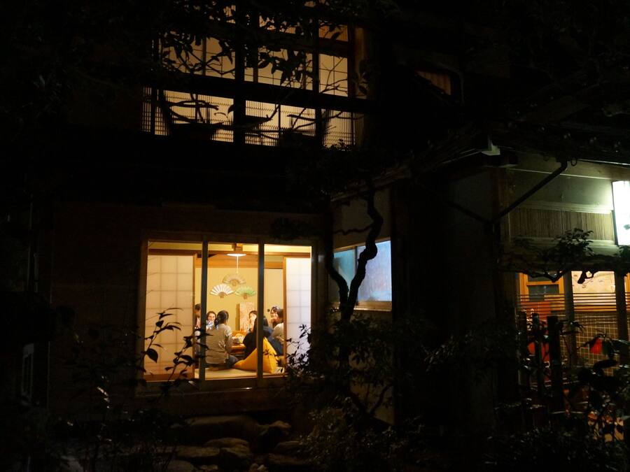 Een traditioneel Japans gebouw 's nachts, met een zichtbare ingang en een verlicht interieur.