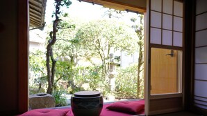 A traditional Japanese room with tatami flooring, a wooden door, and a view of a garden.