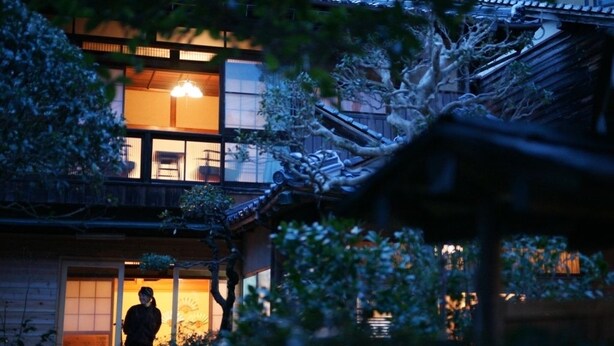 A traditional Japanese building with a wooden exterior and a visible interior with sliding doors and a lantern.