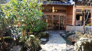 A traditional Japanese building with a stone pathway leading to a wooden entrance.