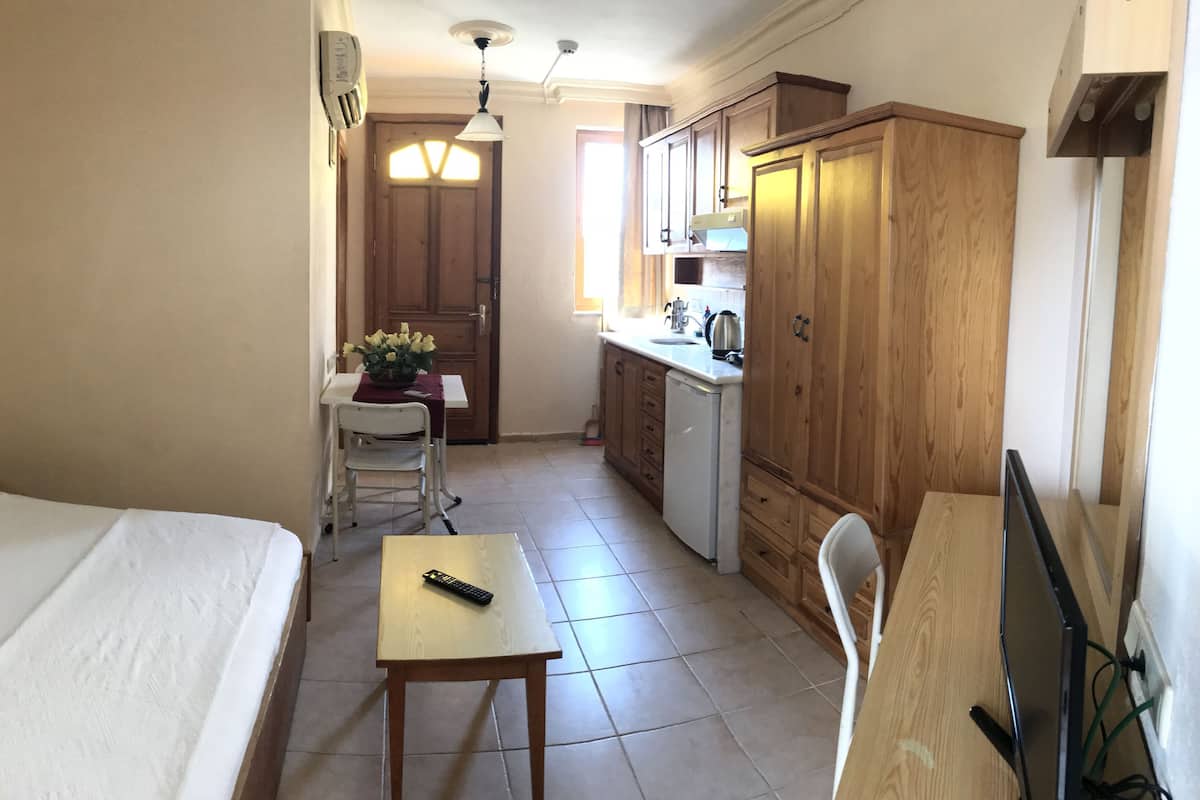 Una habitación de hotel con cama, escritorio, silla, mesita, televisor y armarios de madera.