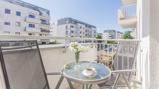 Un balcon avec une table, une chaise et un vase de fleurs.
