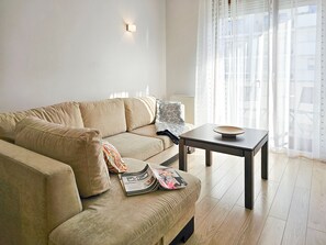 Un salón con un sofá color crema, una mesita con un bol, y una revista sobre el sofá.