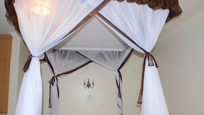 A room with a canopy bed, a chandelier, and a wooden wardrobe. - Tents Hotel (Nairobi)