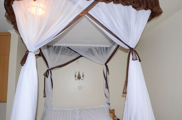 A room with a canopy bed, a chandelier, and a wooden wardrobe. - Tents Hotel (Nairobi)