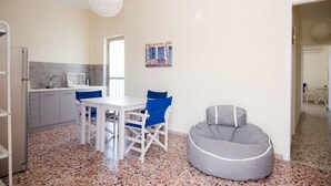 A compact kitchen with a dining area, a gray bean bag chair, and a wall-mounted painting. - Spacious Apartment on the Beachfront (Xylokastro-Evrostina)