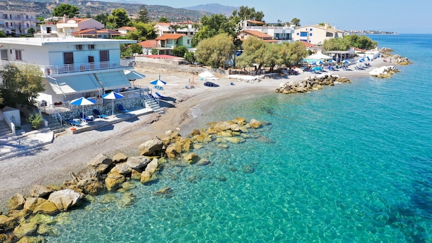 A coastal hotel with clear blue waters, a rocky beach, and a view of the sea. - Spacious Apartment on the Beachfront (Xylokastro-Evrostina)