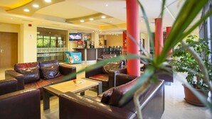 A hotel lobby with leather seating, a coffee station, and a TV screen. - Strandzha Hotel (Varna)