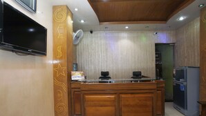 A kitchen with a wooden counter, a refrigerator, and a television mounted on the wall. - Hotel Star Park (Chittagong)