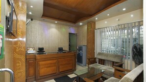 A hotel lobby with a reception desk, seating area, and a refrigerator. - Hotel Star Park (Chittagong)