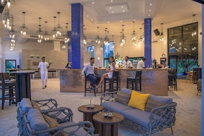 A spacious lounge area with a bar, seating arrangements, and hanging light fixtures.