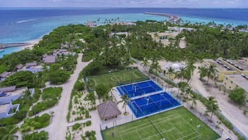 An aerial view of a resort with multiple buildings, a beach, and a tennis court.