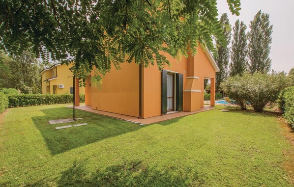 Una casa moderna de dos pisos con un césped cuidado y una piscina al fondo.