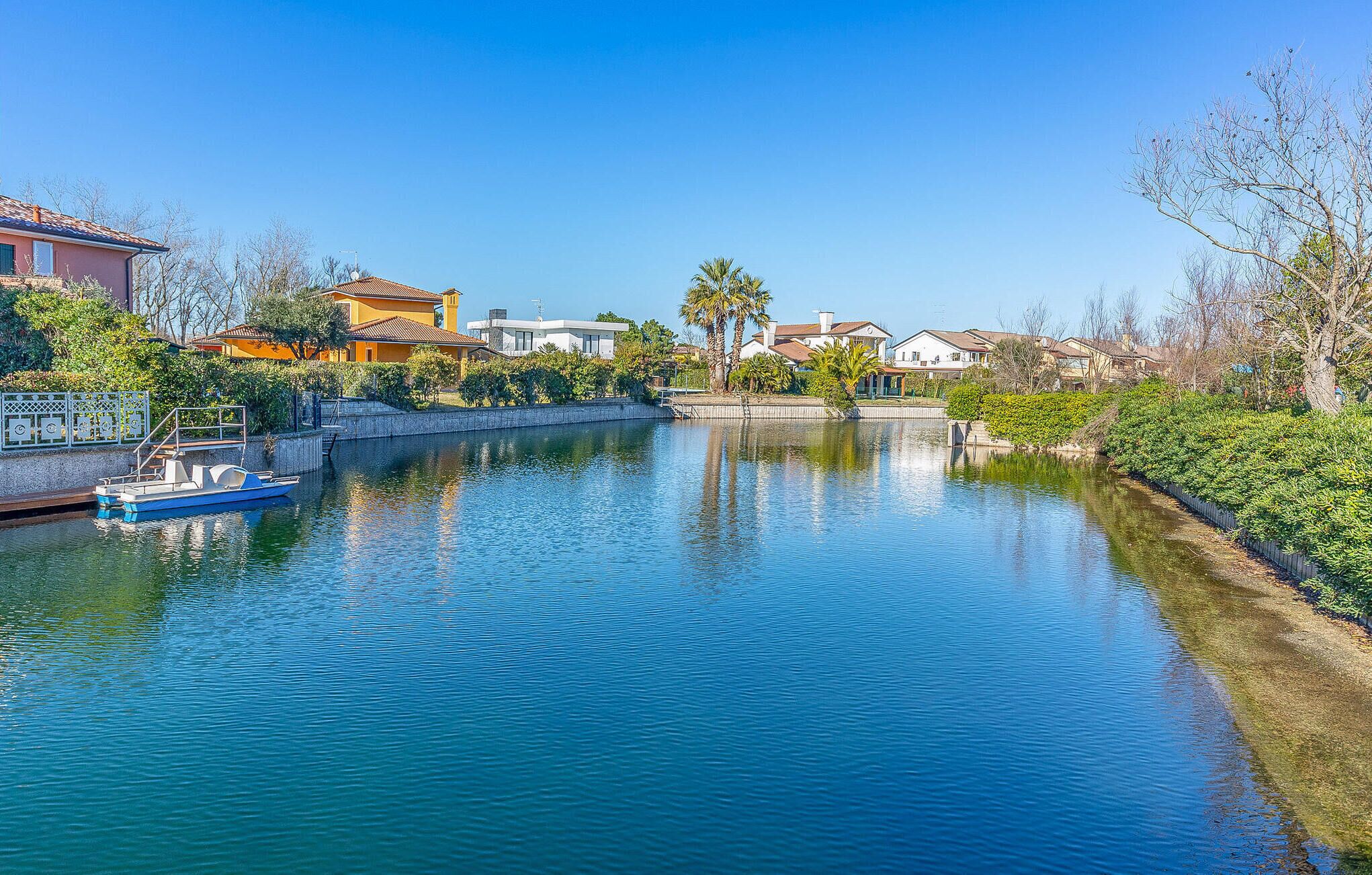 A canal with a boat docked on the left, surrounded by residential buildings and greenery.