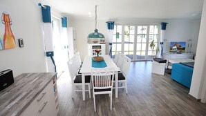Un espacio habitable luminoso y de concepto abierto, con comedor, cocina y ventanas amplias.