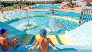 Una piscina amb diverses línies de natació i un tobogan aquàtic.