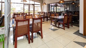 A restaurant with wooden tables and chairs, large windows, and hanging pendant lights. - KATSUYA Inn (Wakayama)