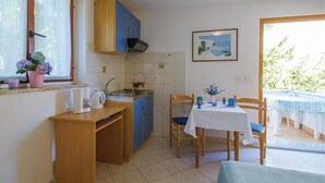 Una cocina compacta con comedor, una ventana con vistas y un cuadro en la pared.