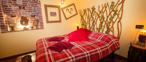 Una habitación acogedora con chimenea de ladrillo, una cama con colcha escocesa y un enrejado de madera con follaje.