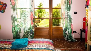 Un dormitorio con cama, cortinas, una ventana y vistas a un jardín.