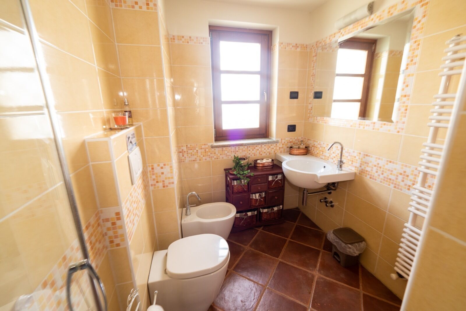 A bathroom with a toilet, sink, and window.