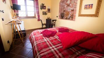 Una camera da letto con un letto, una sedia, un tavolino, una TV e una finestra con tende.