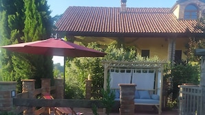 Una casa con techo de tejas, piscina y un patio con una sombrilla roja.