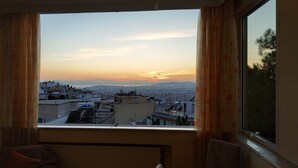 Una habitación con un ventanal grande que da a una vista panorámica de la ciudad al atardecer.