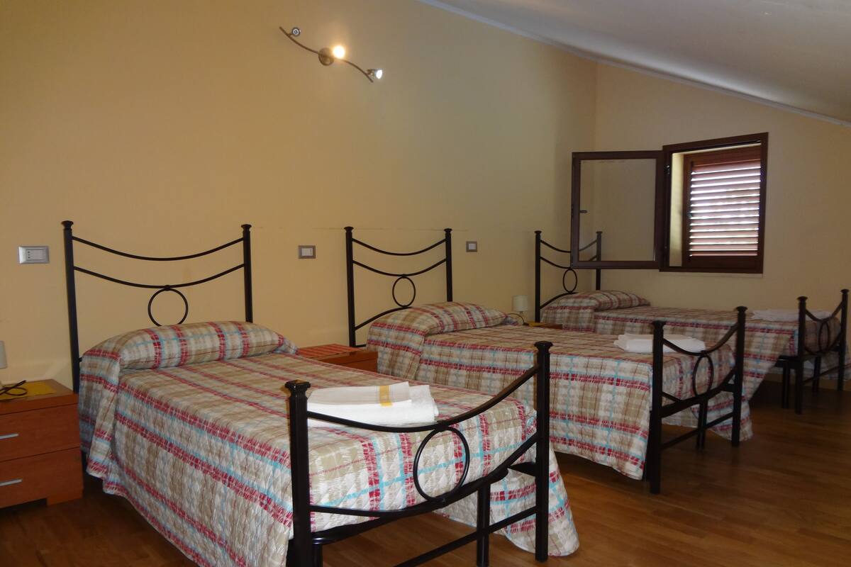 Een slaapkamer met vier bedden, houten vloeren en een spiegel aan de muur.