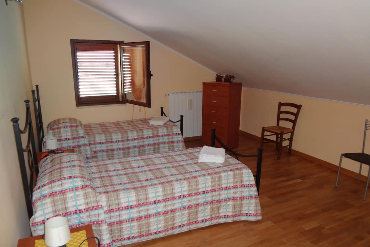 Een slaapkamer met een bed, een stoel, een kaptafel en een raam met jaloezieën.