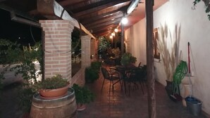 Un espace extérieur aménagé en patio, avec des piliers en briques, des plantes en pot et une pergola en bois.
