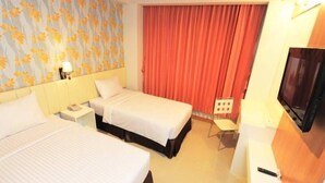 Een hotelkamer met twee bedden, een televisie, een bureau en een stoel.