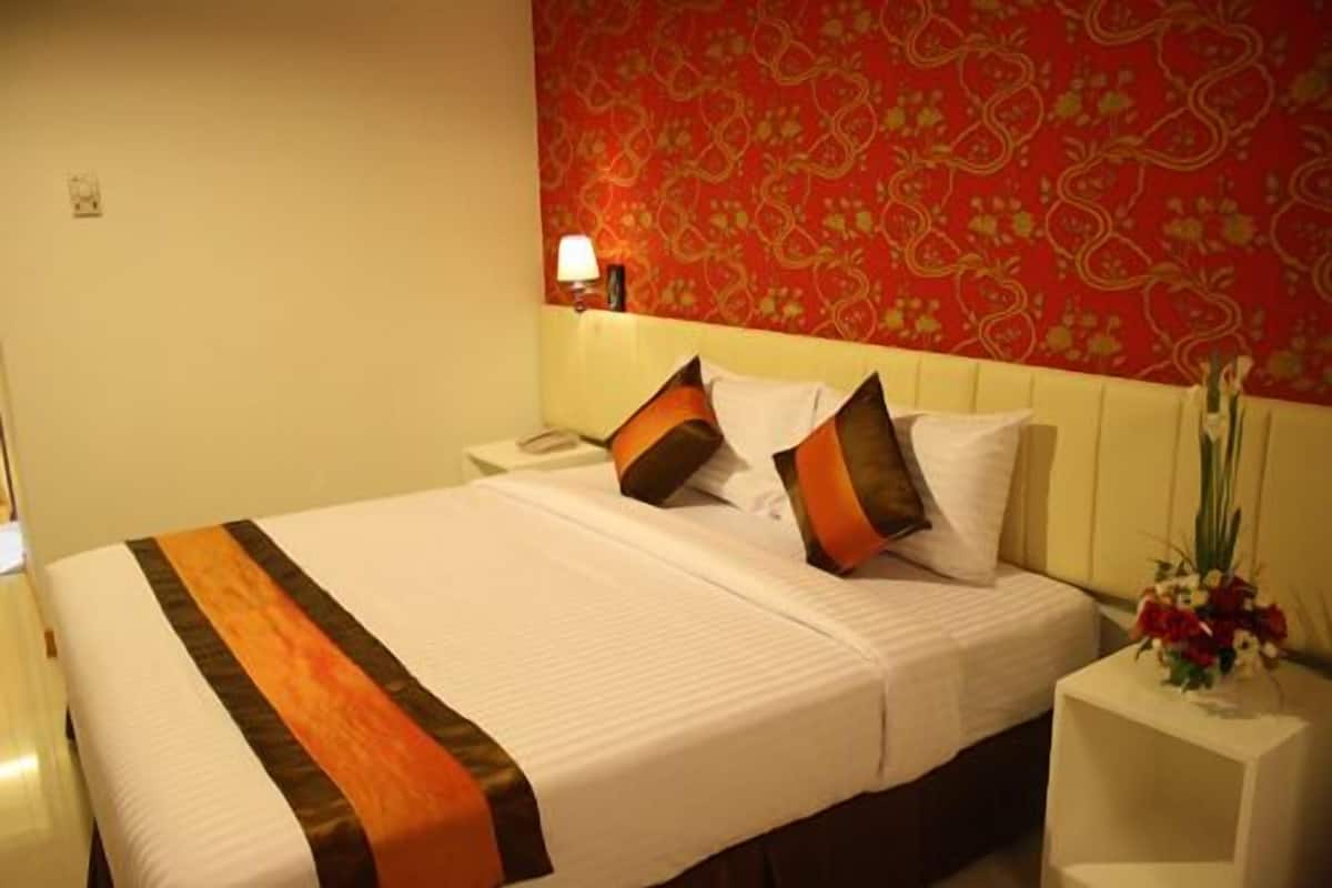 A hotel room with a bed, a nightstand, a lamp, and a floral arrangement.